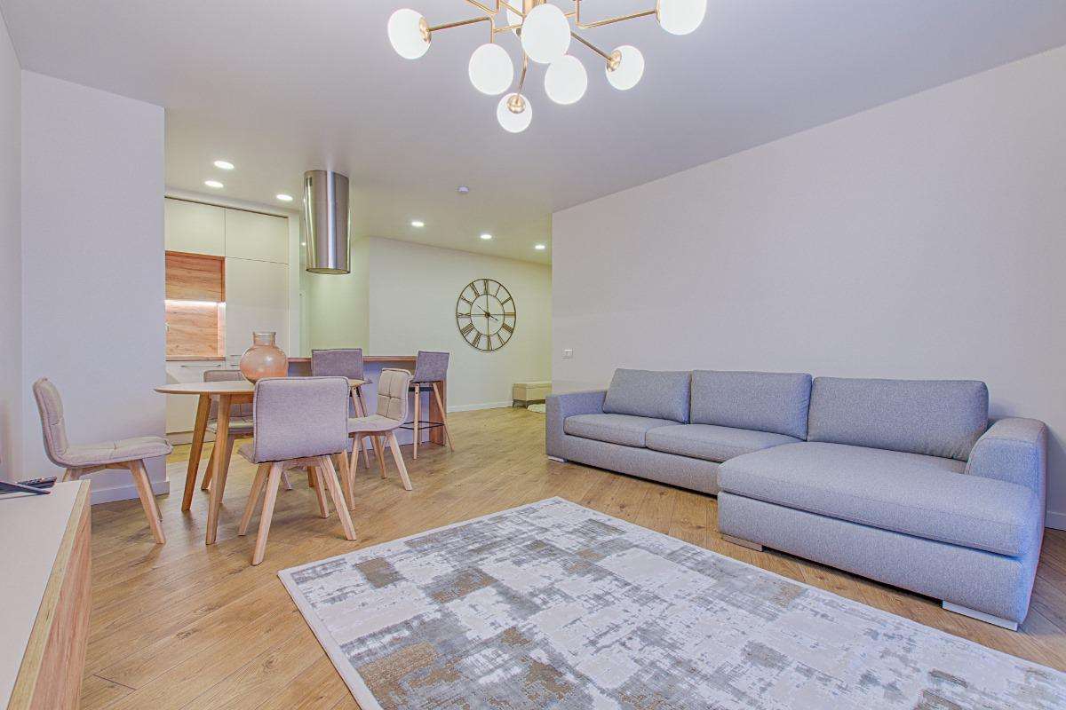 Modern living room interior with gray sectional sofa, wood flooring, and open dining area in Minneapolis home